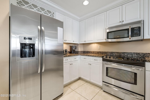 kitchen featuring white cabinets, dark stone counters, light tile patterned floors, stainless steel appliances, and crown molding