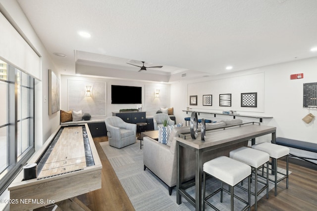 living room featuring ceiling fan, wood-type flooring, a textured ceiling, and plenty of natural light