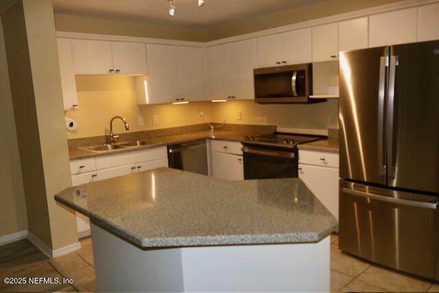 kitchen with light tile patterned floors, appliances with stainless steel finishes, sink, and white cabinets