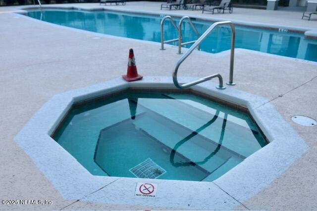 view of swimming pool featuring a community hot tub and a patio