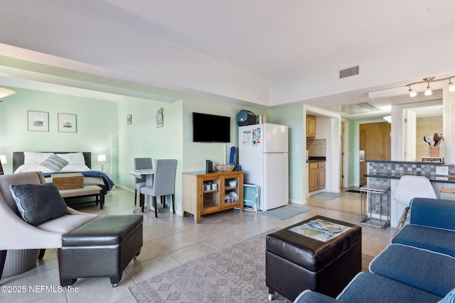 living area with light tile patterned floors, visible vents, and baseboards