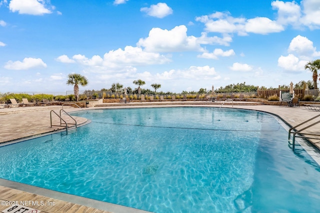 community pool with fence and a patio