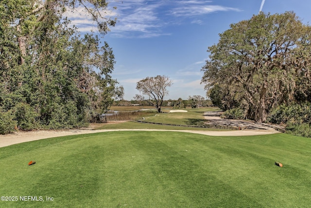 view of community featuring view of golf course and a yard