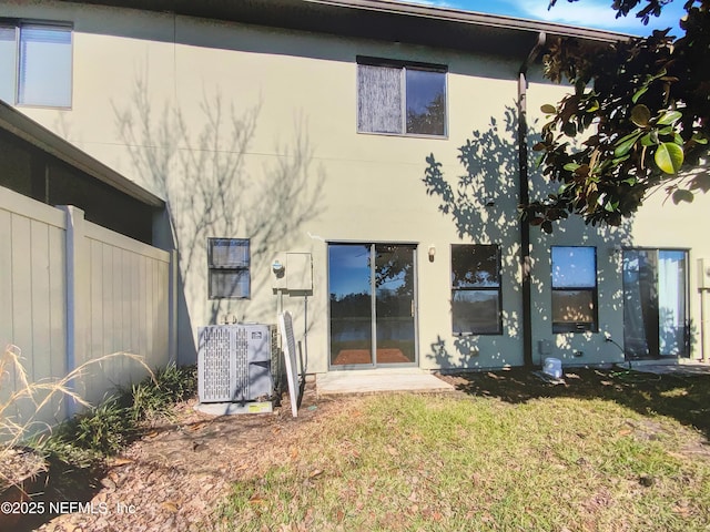 back of property featuring central air condition unit and a yard