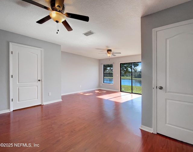 unfurnished room featuring ceiling fan, dark wood-type flooring, and a textured ceiling