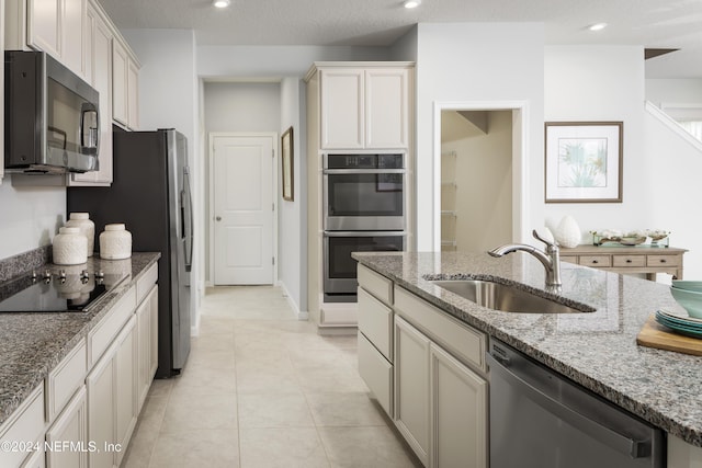 kitchen featuring sink, white cabinetry, light stone countertops, stainless steel appliances, and light tile patterned floors