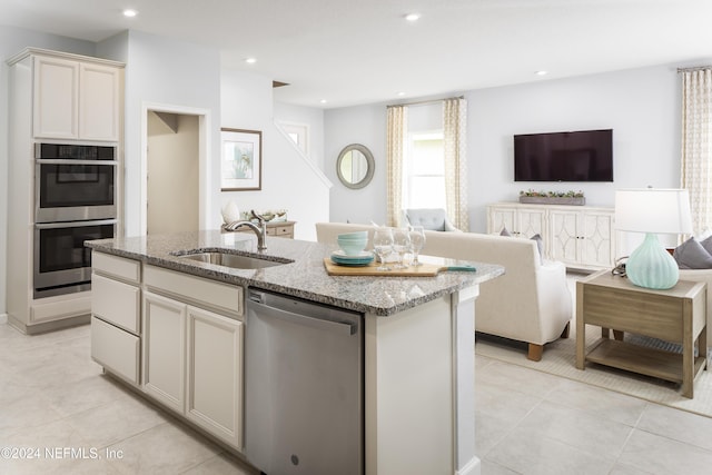 kitchen featuring a kitchen island with sink, light stone countertops, sink, and stainless steel appliances