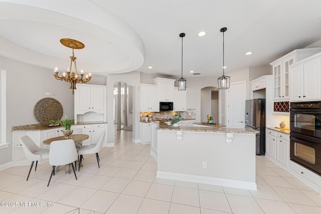 kitchen with arched walkways, glass insert cabinets, white cabinets, a kitchen island, and black appliances