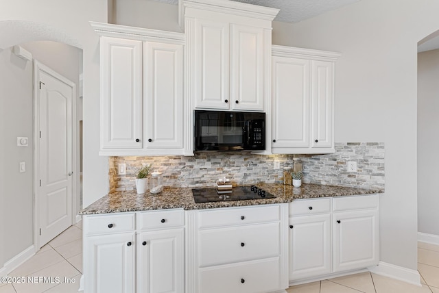 kitchen featuring arched walkways, black appliances, and white cabinetry