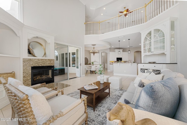 living area featuring light tile patterned floors, a tiled fireplace, and an inviting chandelier