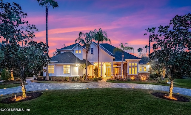 view of front of house with driveway, a lawn, and stucco siding