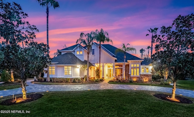 view of front of house with driveway, a lawn, and stucco siding