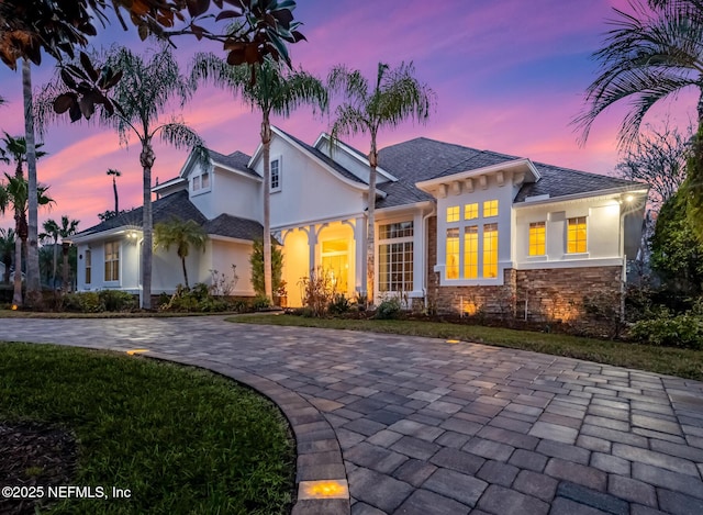 view of front of house with stone siding, a yard, and stucco siding