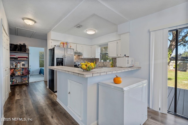 kitchen with decorative backsplash, kitchen peninsula, white cabinetry, stainless steel appliances, and tile counters