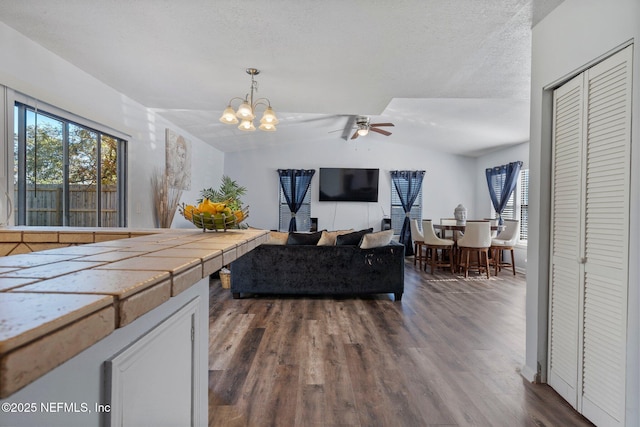 kitchen with decorative light fixtures, vaulted ceiling, tile countertops, white cabinets, and dark hardwood / wood-style flooring