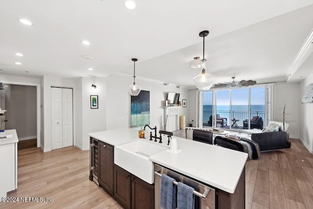 kitchen featuring light hardwood / wood-style floors, dishwasher, sink, pendant lighting, and a center island with sink