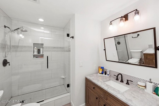 bathroom with tasteful backsplash, toilet, an enclosed shower, and vanity