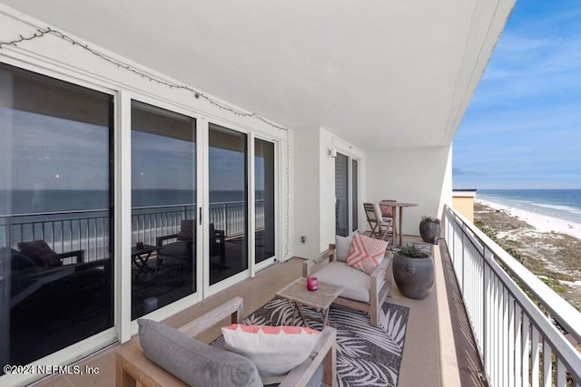 balcony with a water view and a view of the beach