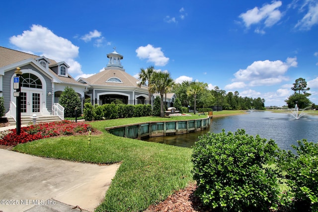 view of home's community with a lawn and a water view