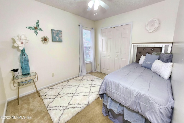 carpeted bedroom featuring ceiling fan, a closet, and a textured ceiling