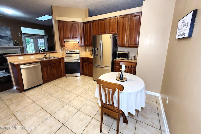 kitchen with light tile patterned flooring, decorative backsplash, stainless steel appliances, a textured ceiling, and french doors