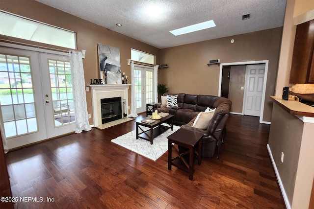 living room featuring french doors, dark hardwood / wood-style flooring, a textured ceiling, and a wealth of natural light