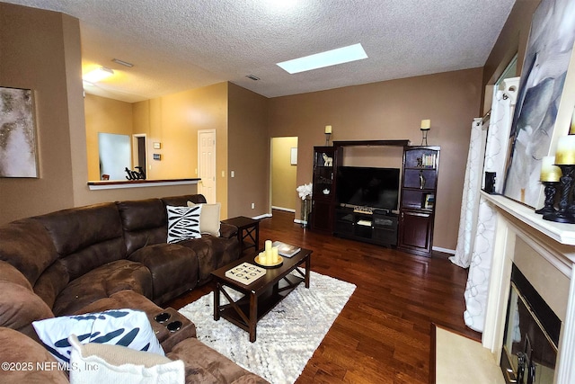 living room featuring dark hardwood / wood-style flooring, a skylight, and a textured ceiling