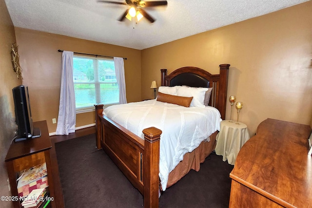 bedroom featuring dark colored carpet, a textured ceiling, and ceiling fan