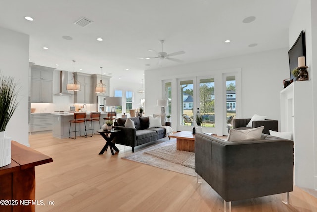 living room with light wood-type flooring, ceiling fan, french doors, and plenty of natural light