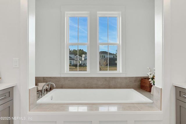 bathroom with a relaxing tiled tub and vanity