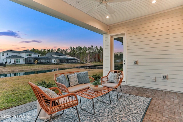 patio terrace at dusk featuring ceiling fan, outdoor lounge area, and a yard