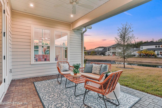 patio terrace at dusk with ceiling fan, outdoor lounge area, and a yard