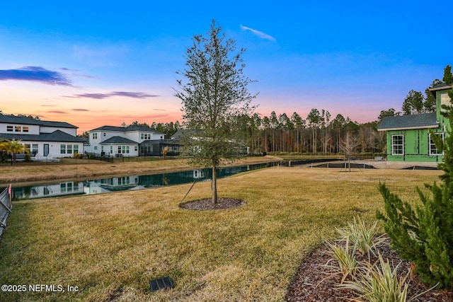 yard at dusk featuring a water view