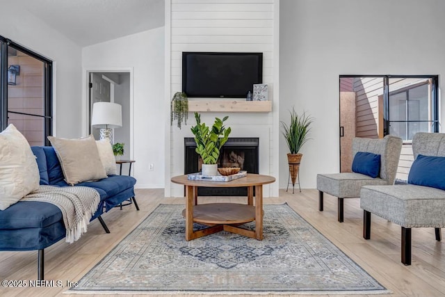 living room featuring lofted ceiling, a fireplace, and light hardwood / wood-style flooring