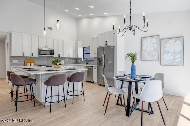 kitchen featuring stainless steel appliances, decorative light fixtures, and white cabinets