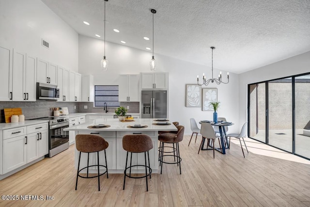 kitchen with pendant lighting, white cabinetry, appliances with stainless steel finishes, and a kitchen island