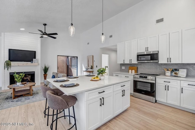 kitchen featuring appliances with stainless steel finishes, a center island, hanging light fixtures, and white cabinets