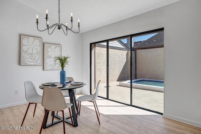 dining area with an inviting chandelier, a textured ceiling, and light wood-type flooring