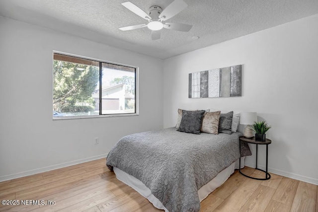 bedroom with ceiling fan, light hardwood / wood-style flooring, and a textured ceiling