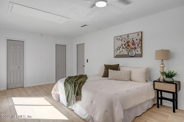 bedroom with multiple closets, ceiling fan, and light hardwood / wood-style flooring