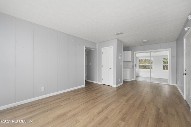 unfurnished living room featuring light hardwood / wood-style floors and a textured ceiling