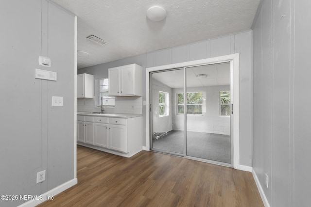 kitchen featuring dark hardwood / wood-style flooring, a textured ceiling, tasteful backsplash, and white cabinets