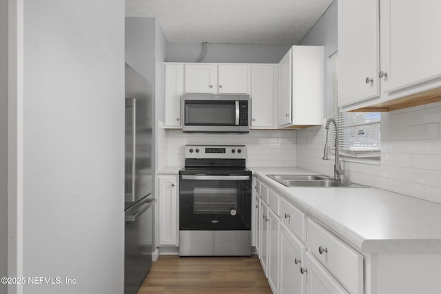 kitchen featuring tasteful backsplash, white cabinetry, appliances with stainless steel finishes, and sink