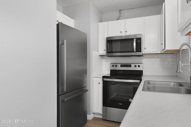 kitchen featuring sink, white cabinetry, a textured ceiling, appliances with stainless steel finishes, and backsplash