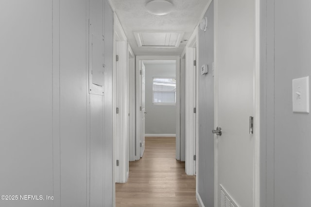 hall with a textured ceiling and light wood-type flooring