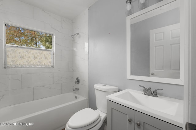 full bathroom featuring tiled shower / bath, vanity, and toilet