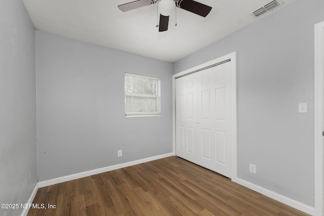 unfurnished bedroom with ceiling fan, dark hardwood / wood-style floors, and a closet