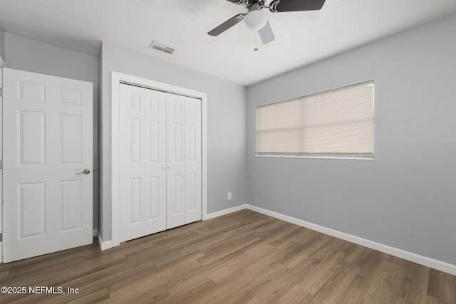 unfurnished bedroom featuring ceiling fan, hardwood / wood-style floors, and a closet