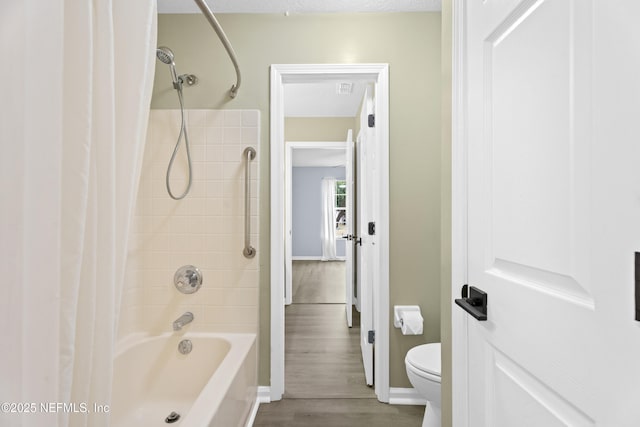 bathroom featuring tiled shower / bath, wood-type flooring, and toilet