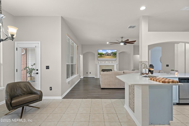 kitchen with sink, light tile patterned floors, dishwasher, pendant lighting, and ceiling fan with notable chandelier